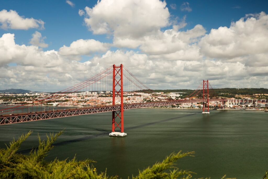 A stunning view of the 25 de Abril Bridge crossing the Tagus River against a city backdrop in Lisbon, Portugal.