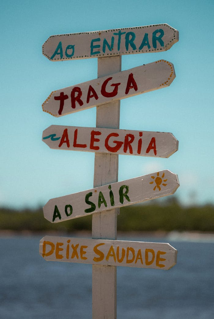 Wooden signpost with vibrant Portuguese phrases at the beach.